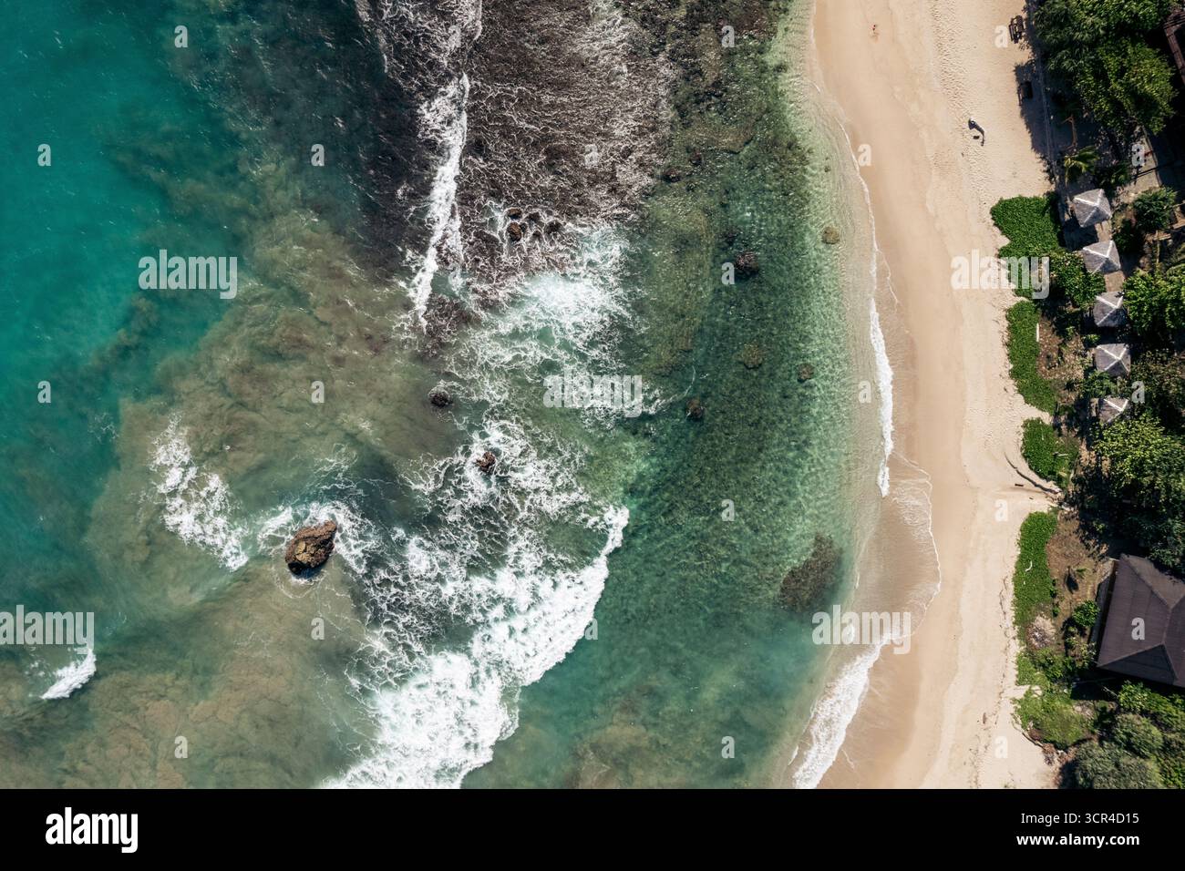 Blick aus der Vogelperspektive auf ein türkisfarbenes Meer und Sandstrand mit üppiger grüner Vegetation. Momong Lampuuk ein Strand in Aceh, Sumatra, Indonesien Stockfoto