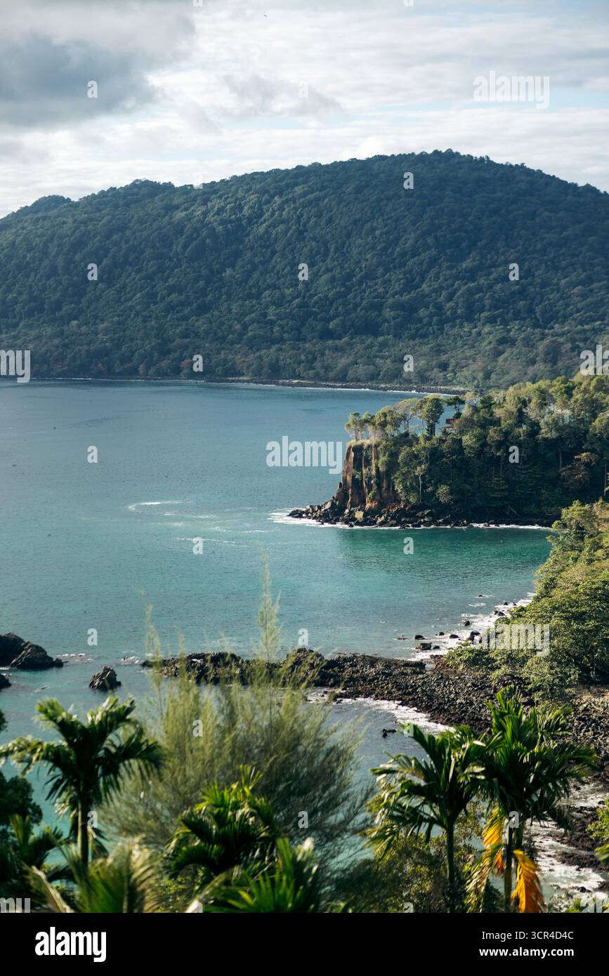 Üppige Insellandschaft mit felsigen Klippen und türkisfarbenem Meer unter einem bewölkten Himmel. Paya, auf We Island in Aceh, Sumatra, Indonesien Stockfoto
