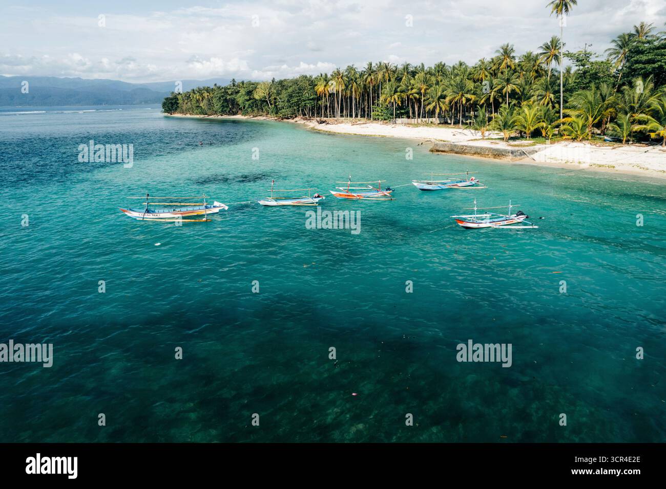 Tropischer Strand mit türkisfarbenem Wasser, Palmen und Booten vor der Küste. Krui-Küste in Lampung, Indonesien Stockfoto