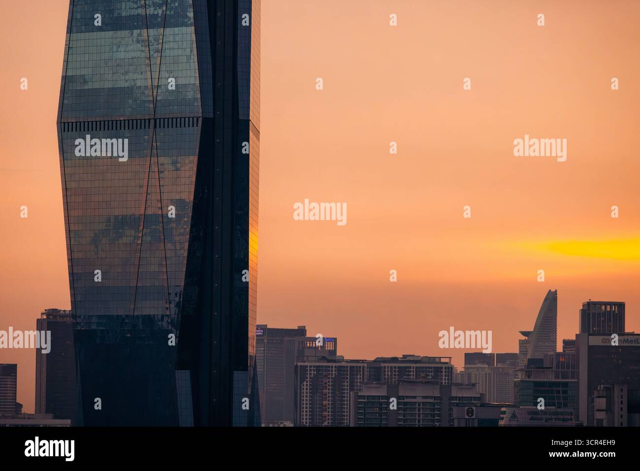 Eine Skyline der Stadt mit modernen Wolkenkratzern bei Sonnenuntergang und einem warmen orangefarbenen Himmel. Kuala Lumpur, Malaysia Stockfoto