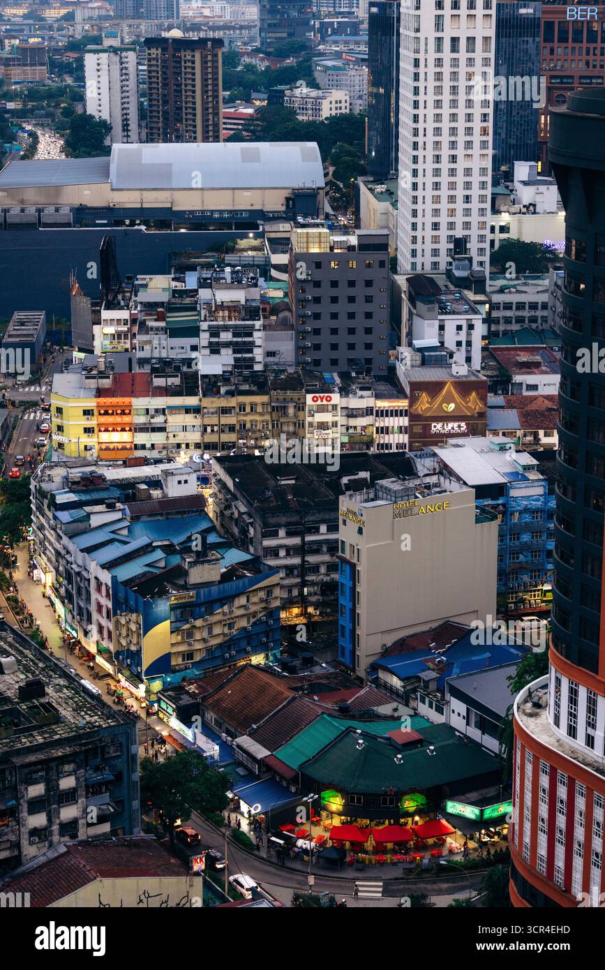 Blick aus der Vogelperspektive auf die geschäftige Skyline der Stadt mit dichten Gebäuden und pulsierendem Stadtleben in der Abenddämmerung. Kuala Lumpur, Malaysia Stockfoto