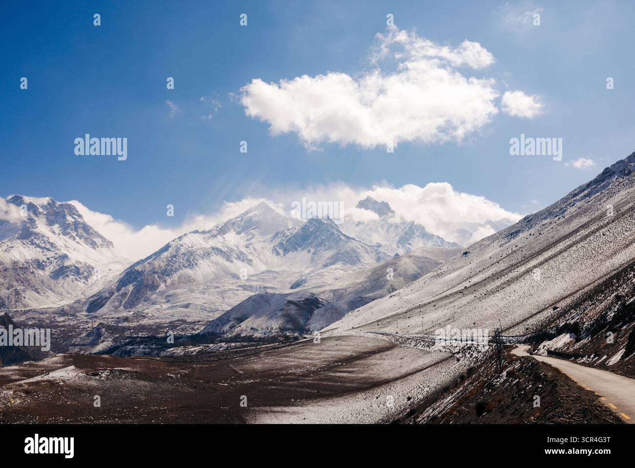 Majestätische schneebedeckte Berge unter einem klaren blauen Himmel mit einem gewundenen Pfad an einem sonnigen Tag. F042, Annapurna, Mustang District, Provinz Gandaki, Nepal Stockfoto