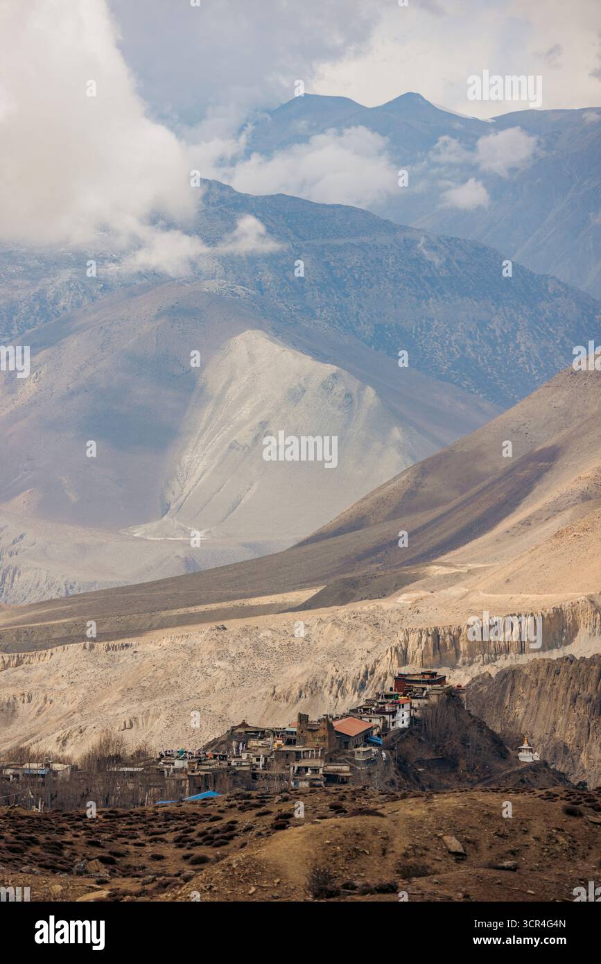Ein abgelegenes Bergdorf, eingebettet in eine karge, zerklüftete Landschaft mit hohen Gipfeln und Wolken. Muktinath, Annapurna, Bezirk Mustang, Provinz Gandaki, Nepal Stockfoto