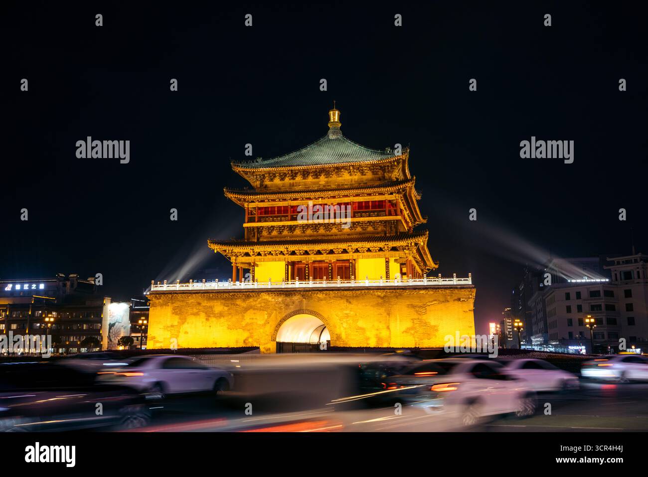 Beleuchtetes historisches Gebäude bei Nacht mit verschwommenen Autolampen vorbeiziehen. Glockenturm von Xi'an, China Stockfoto