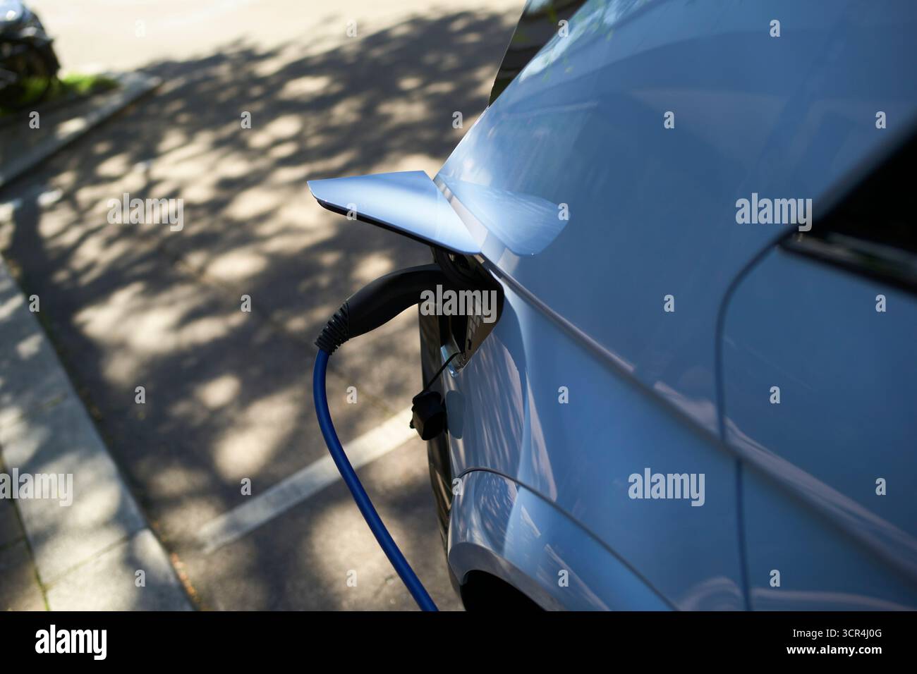 Elektroauto lädt unter Sonnenlicht auf einem Parkplatz auf. Stuttgart, Deutschland Stockfoto
