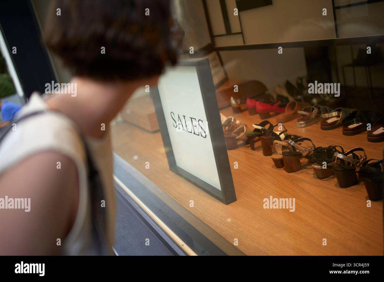 Frau, die auf Schuhladen mit Verkaufsschild blickt. Deutschland Stockfoto