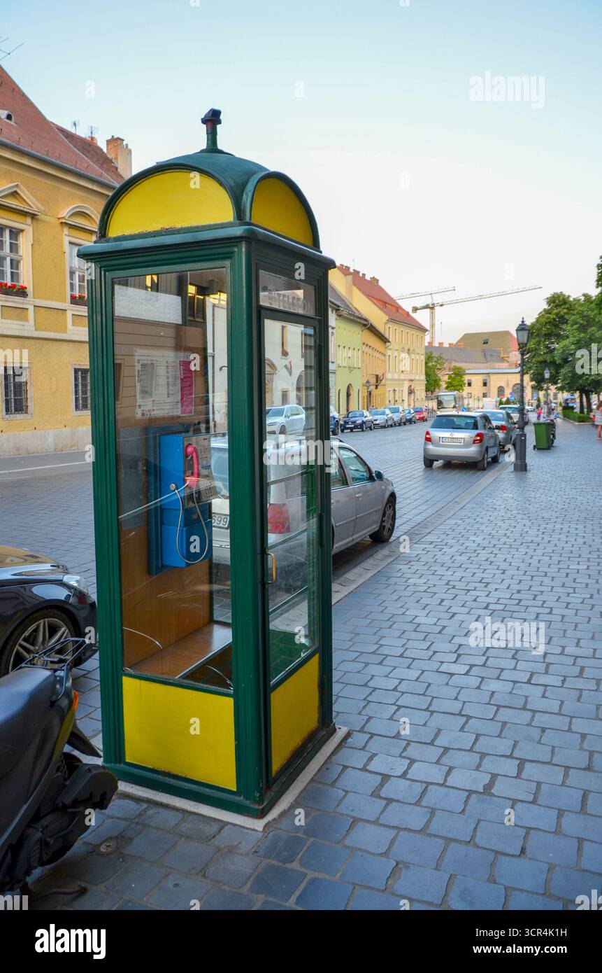 Budapest, Ungarn – 10. Juli 2017: Traditioneller Vintage-Telefonstand mit gelben und grünen Farben auf einer kopfsteingepflasterten Straße. Stockfoto