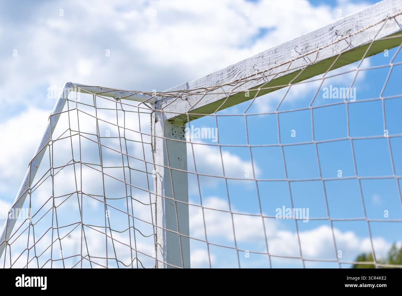 Detaillierte Ansicht der alten Fußballtorecke und des Netzes unter wolkenblauem Himmel. Stockfoto