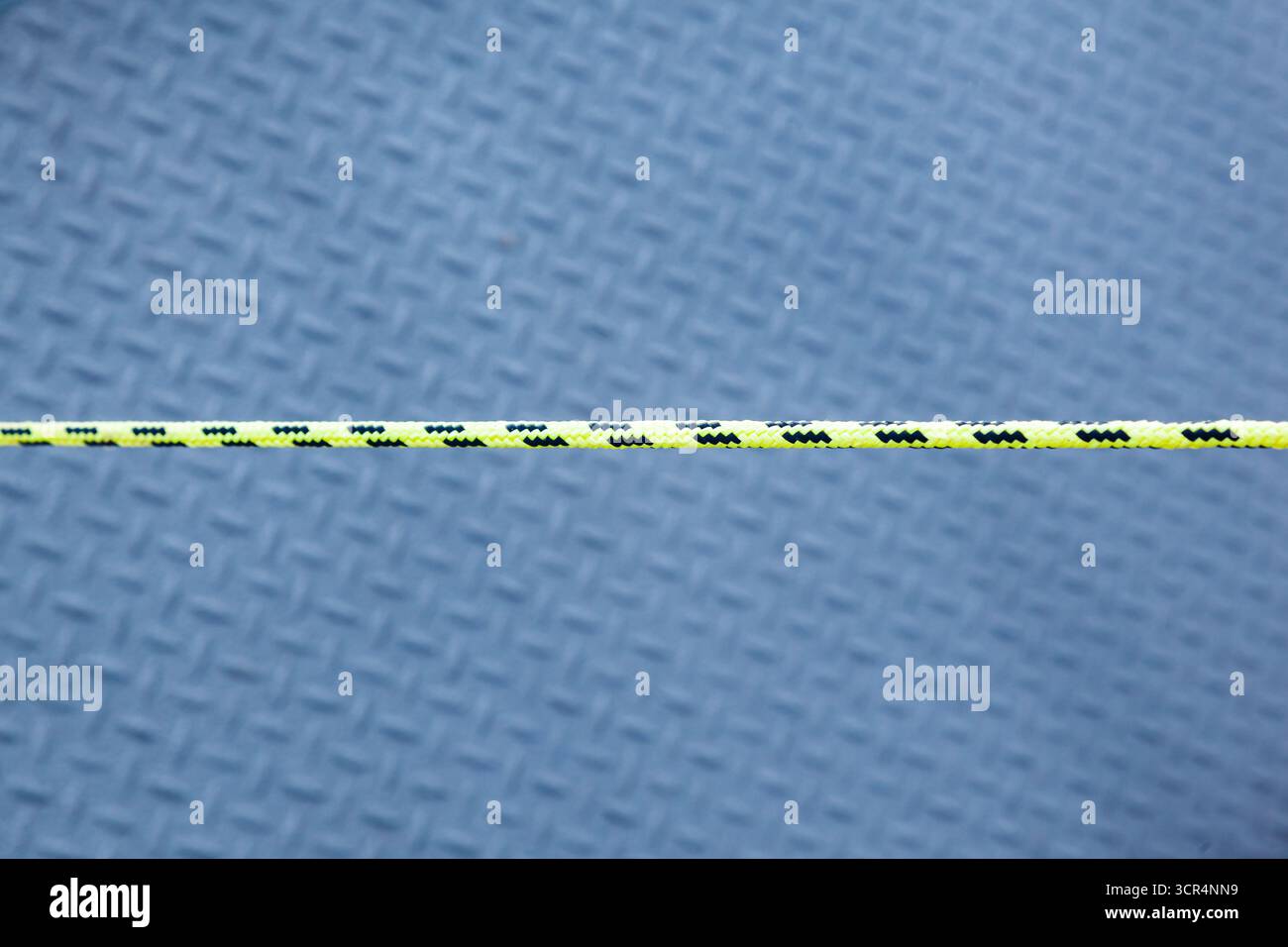 Buntes Segelseil auf einem strukturierten Stahl-Welldeck eines Schiffes, Nahaufnahme Stockfoto
