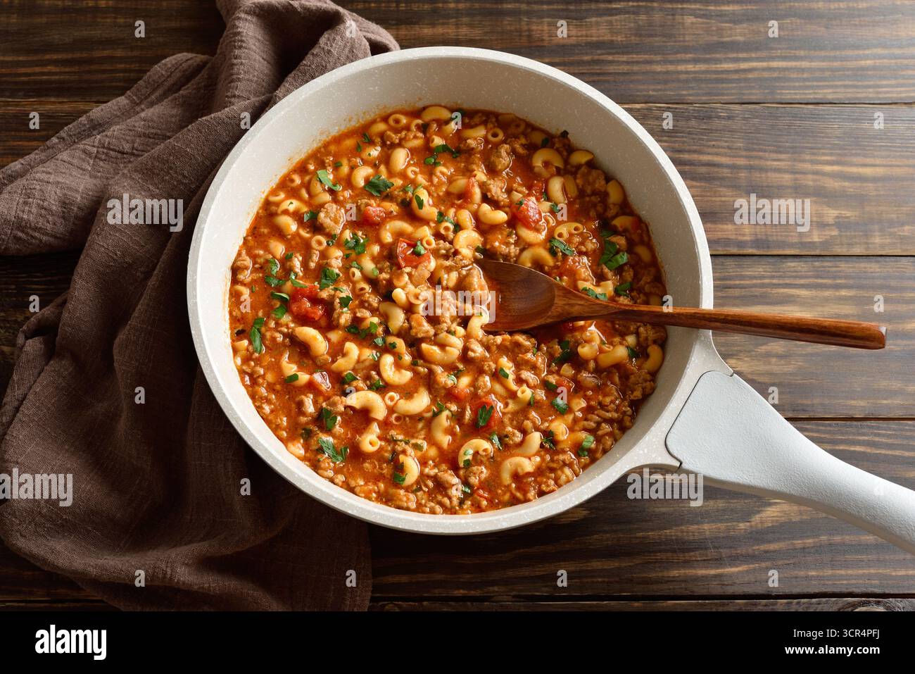 Gericht mit gemahlenem Rindfleisch, Gemüse und Nudeln in Tomatensauce in der Pfanne auf hölzernem Hintergrund. Nahansicht Stockfoto