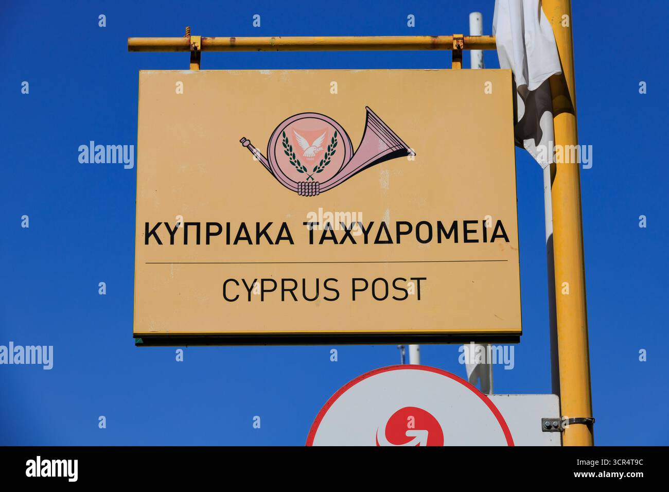 Postschild Zyperns, gelb gegen blauem Himmel. Larnaka, Zypern. Stockfoto