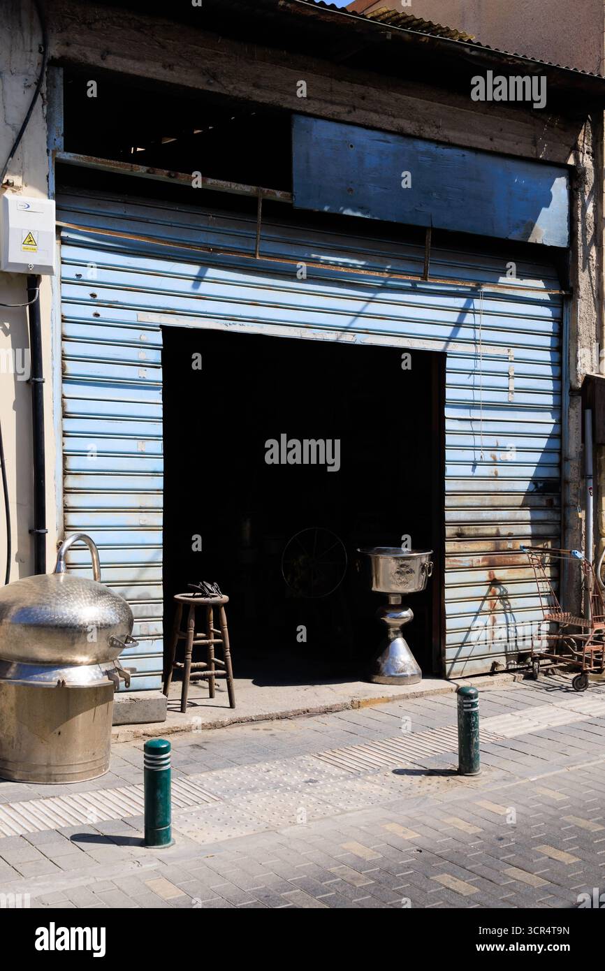 Traditionelle zypriotische Metallschmiedewerkstatt mit verschlossener Tür und Fertigwaren auf dem Bürgersteig. Larnaka, Zypern. Stockfoto