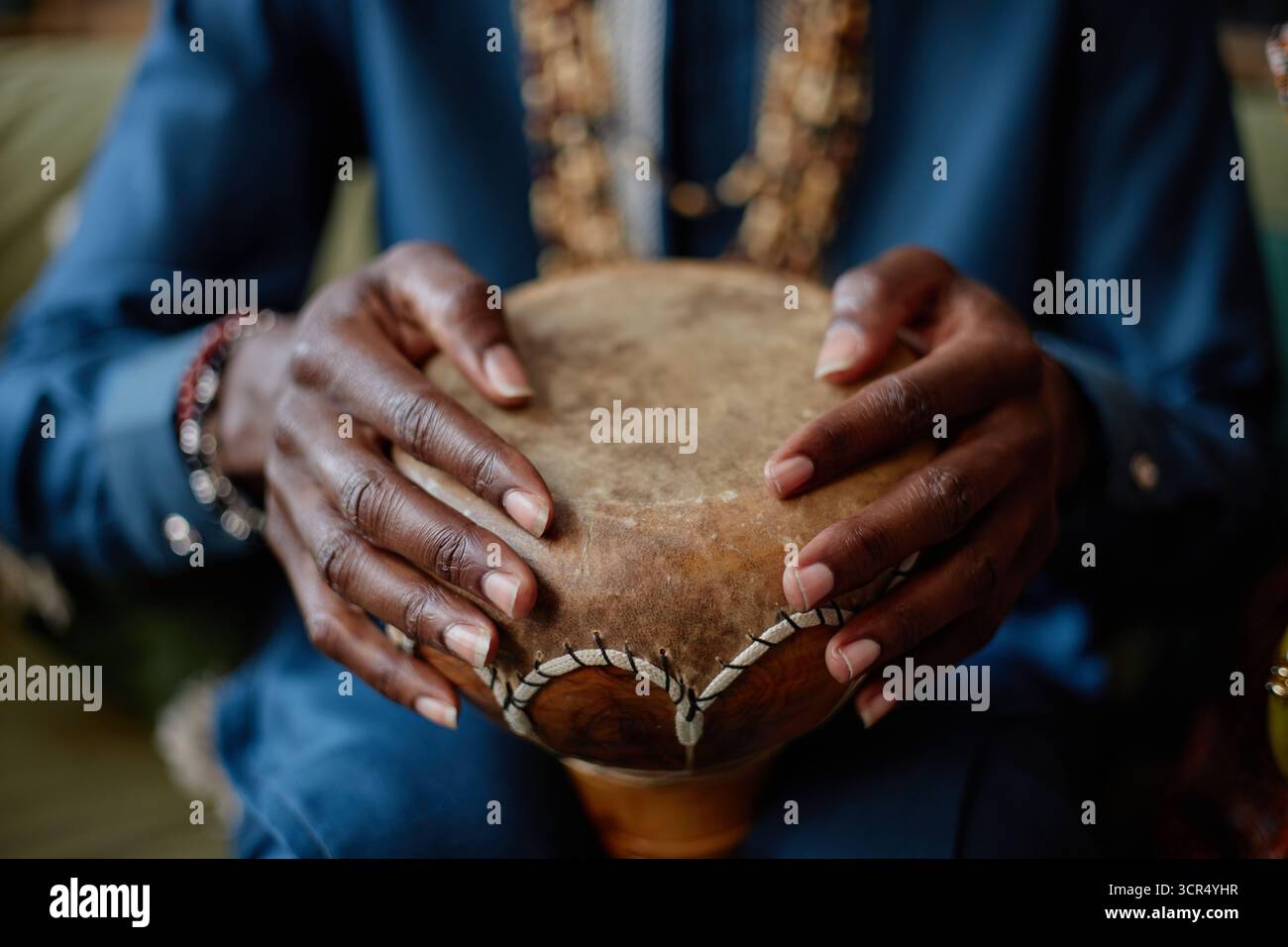 Schwarzer Mann spielt traditionelle Trommel während der Kwanzaa-Feier drinnen Stockfoto