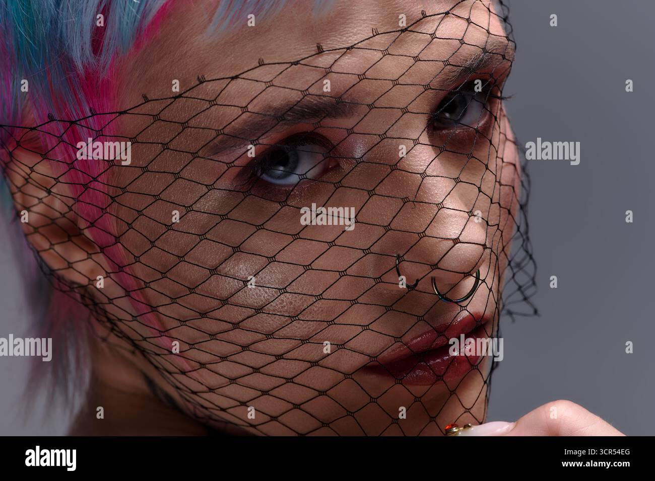 Eine junge Frau mit kurzen, lebendigen Haaren posiert kreativ und verkörpert die moderne Jugendkultur. Stockfoto