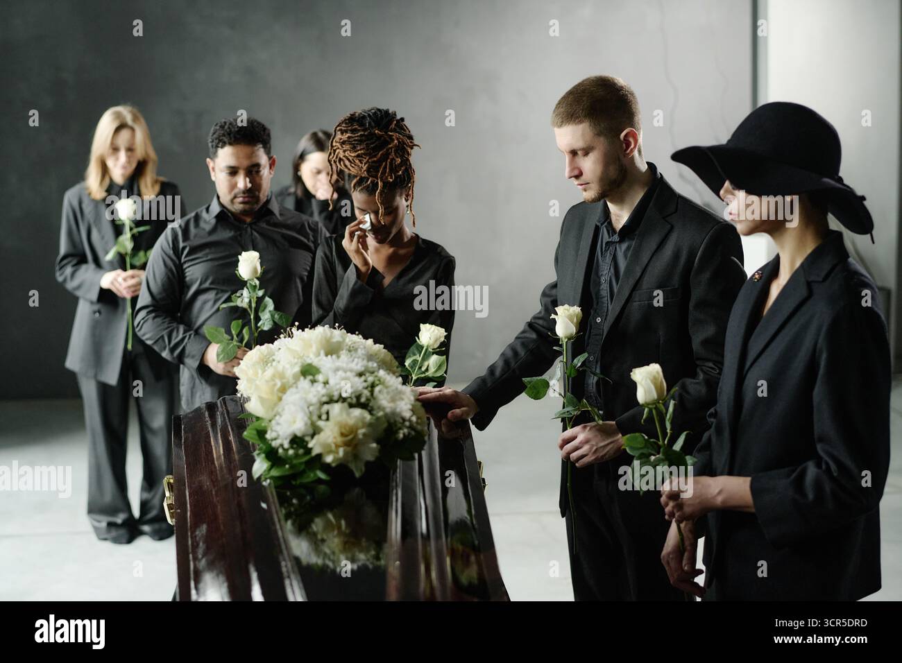 Verschiedene junge Erwachsene trauern bei der Trauerfeier Holding Roses Stockfoto