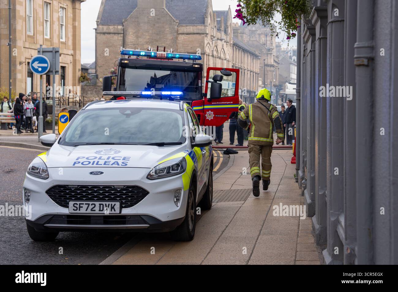 Hier ist ein Feuerwehrmann, der zum Brandort auf der Nairn High Street in Highlands, Schottland, rennt. Polizei und SFRS, Schottischer Feuerwehr- und Rettungsdienst Stockfoto
