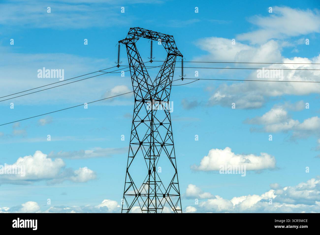 Hochspannungsleitungen gegen einen hellblauen Himmel mit verstreuten Wolken, Puy de Dome, Auvergne Rhone Alpes, Frankreich Stockfoto