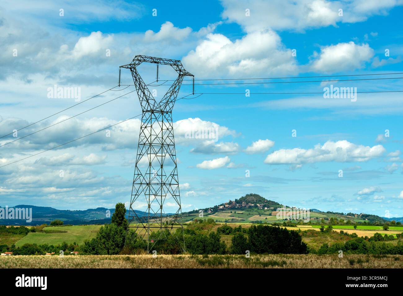 Hochspannungsleitungen gegen einen hellblauen Himmel mit verstreuten Wolken, Puy de Dome, Auvergne Rhone Alpes, Frankreich Stockfoto