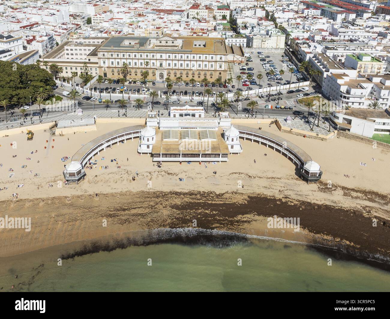 Aus der Vogelperspektive auf den berühmten Strand Playa de la Caleta geküsst von goldenem Sonnenlicht, eingerahmt von dem historischen Balneario de la Palma und den Stadtgebäuden, Cádiz, Andalusien, Spanien. Stockfoto