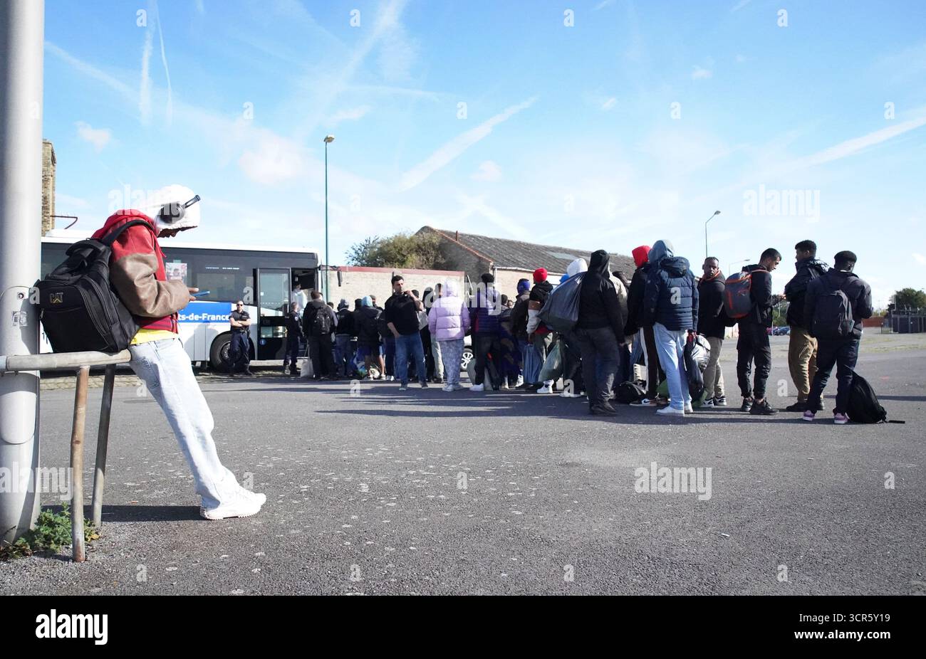 Menschen, die als Migranten gelten, halten ihre Sachen, während sie in Gravelines, Frankreich, an Bord eines lokalen Busses stehen. Bilddatum: Montag, 29. September 2025. Stockfoto