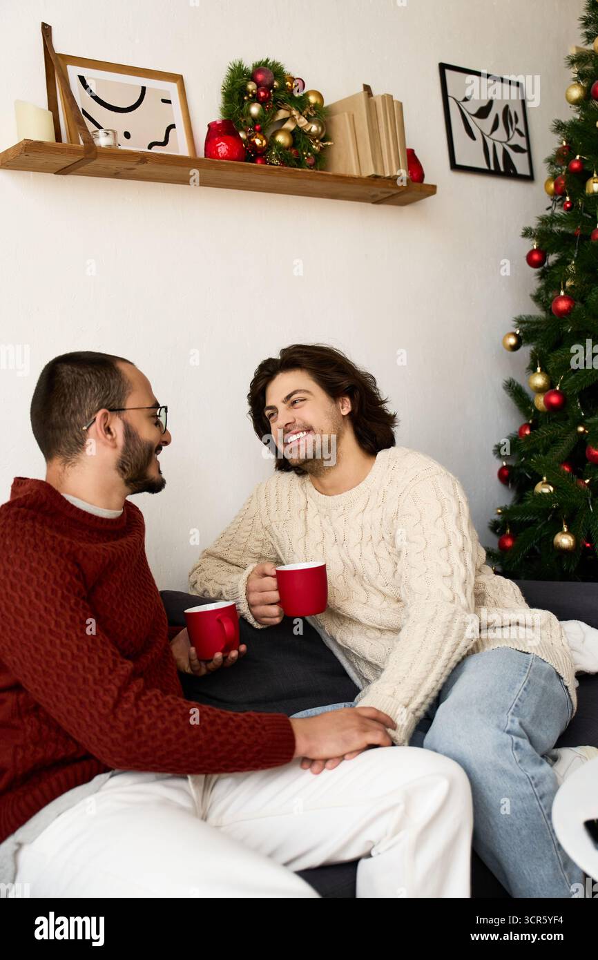 Zwei Männer teilen sich ein warmes Lächeln und festliche Drinks, während sie sich zu Hause in Gesellschaft genießen. Stockfoto