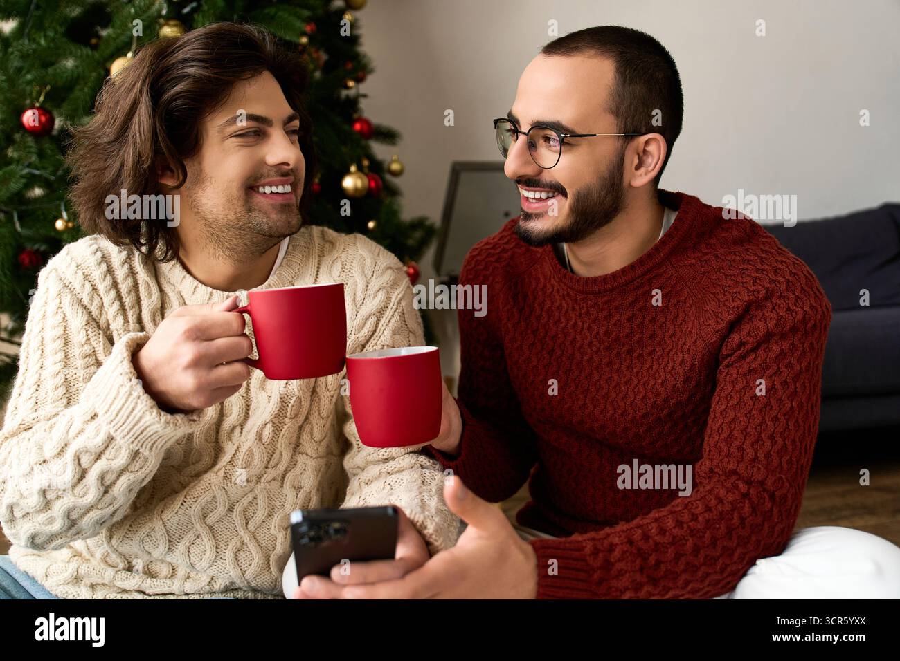 Zwei Männer teilen fröhliche Momente zu Hause, genießen festliche Drinks und sich gegenseitig Gesellschaft. Stockfoto