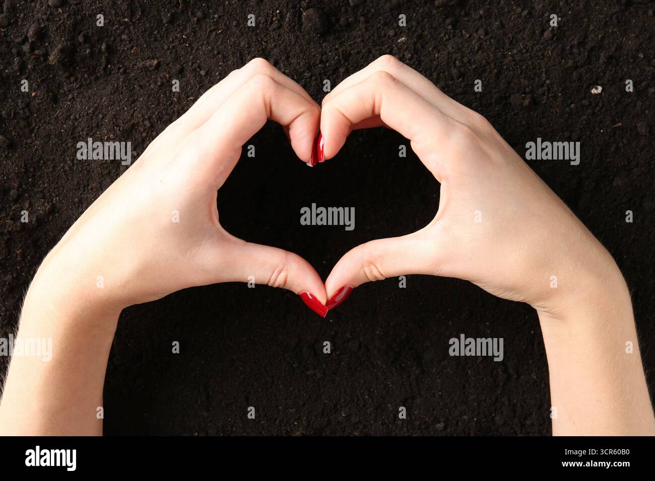 Frau macht Herzgeste in der Nähe von frischem Boden, Draufsicht Stockfoto