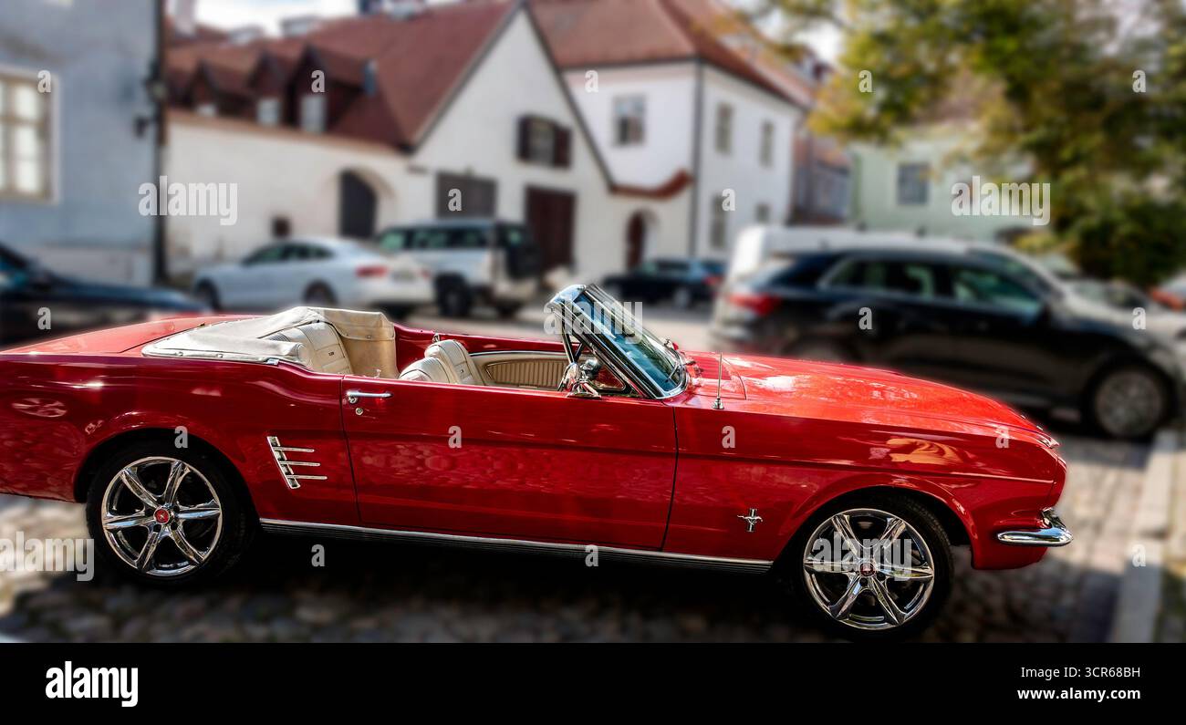 Klassisches rotes Ford Mustang Cabrio, das auf der Kopfsteinpflasterstraße in Tallinn, Estland, geparkt ist, Oldtimer aus Amerika, der vor der historischen Altstadt glänzt Stockfoto