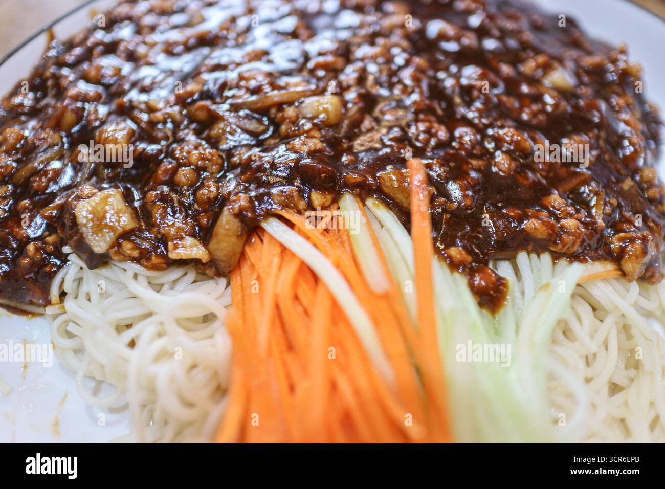 Nahaufnahme chinesischer Zha Jiang Mian-Nudeln mit süßer Bohnenpaste, Karotten- und Gurkenstreifen, authentisches Street Food-Gericht aus Bangkok Chinatown. Stockfoto