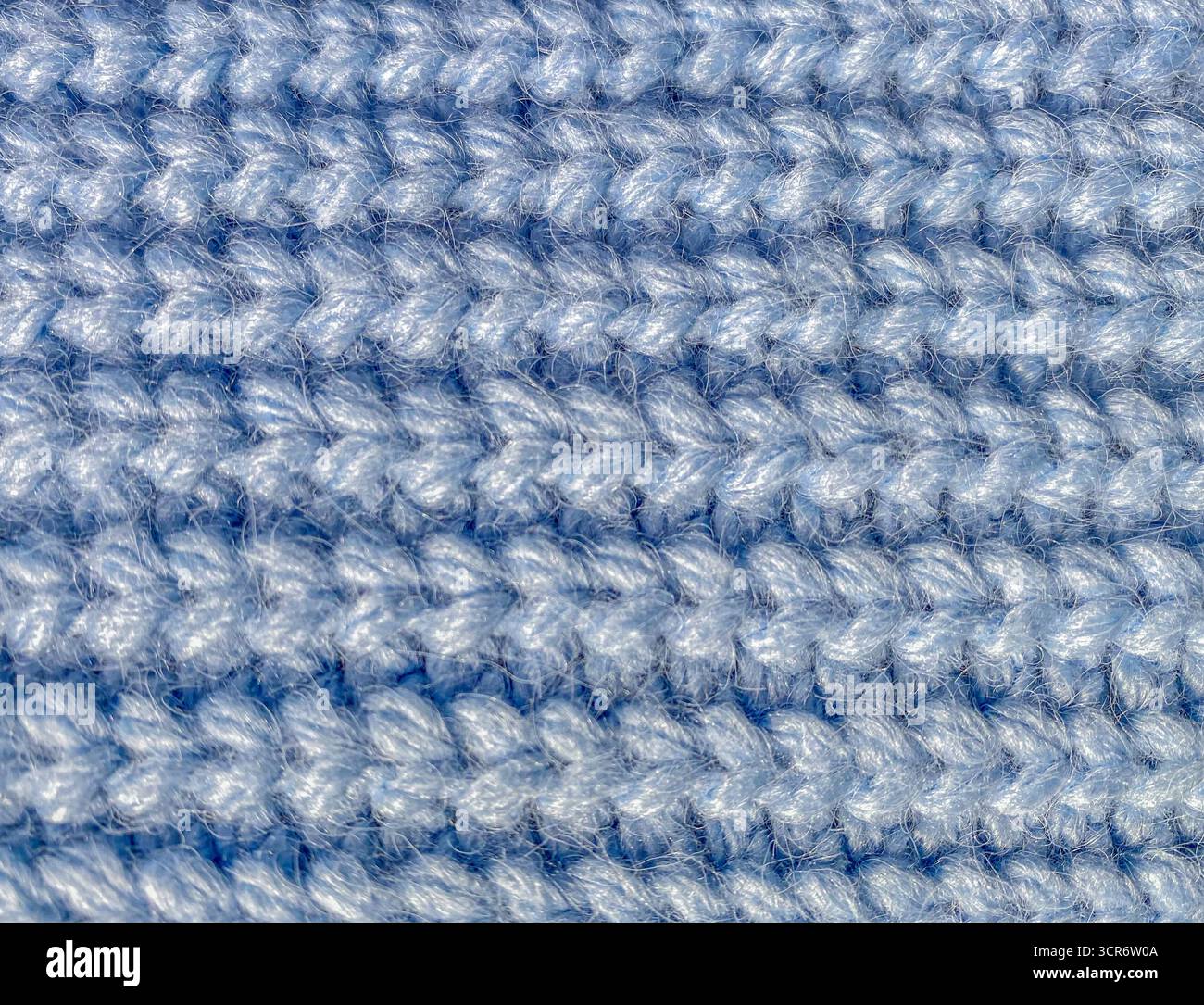Eine Makroansicht von blauem Strickgewebe, die die Struktur und das dicke Garn zeigt. Die weichen Fasern aus kuscheligem und strapazierfähigem Material. Stockfoto