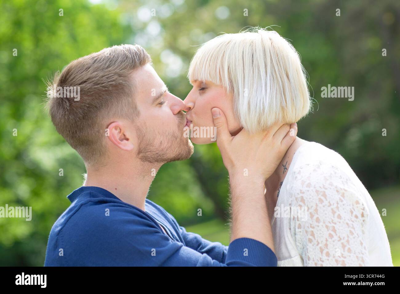 Ein verliebtes Paar steht auf einer Wiese und küsst Stockfoto