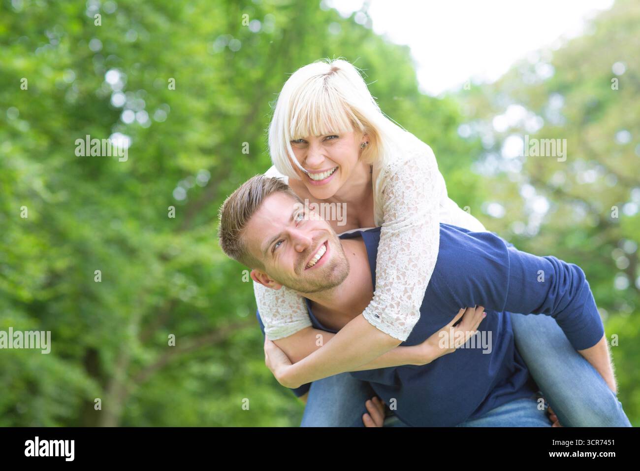Ein junges, verliebtes Paar auf einer Wiese, er trägt ihr Huckepack Stockfoto