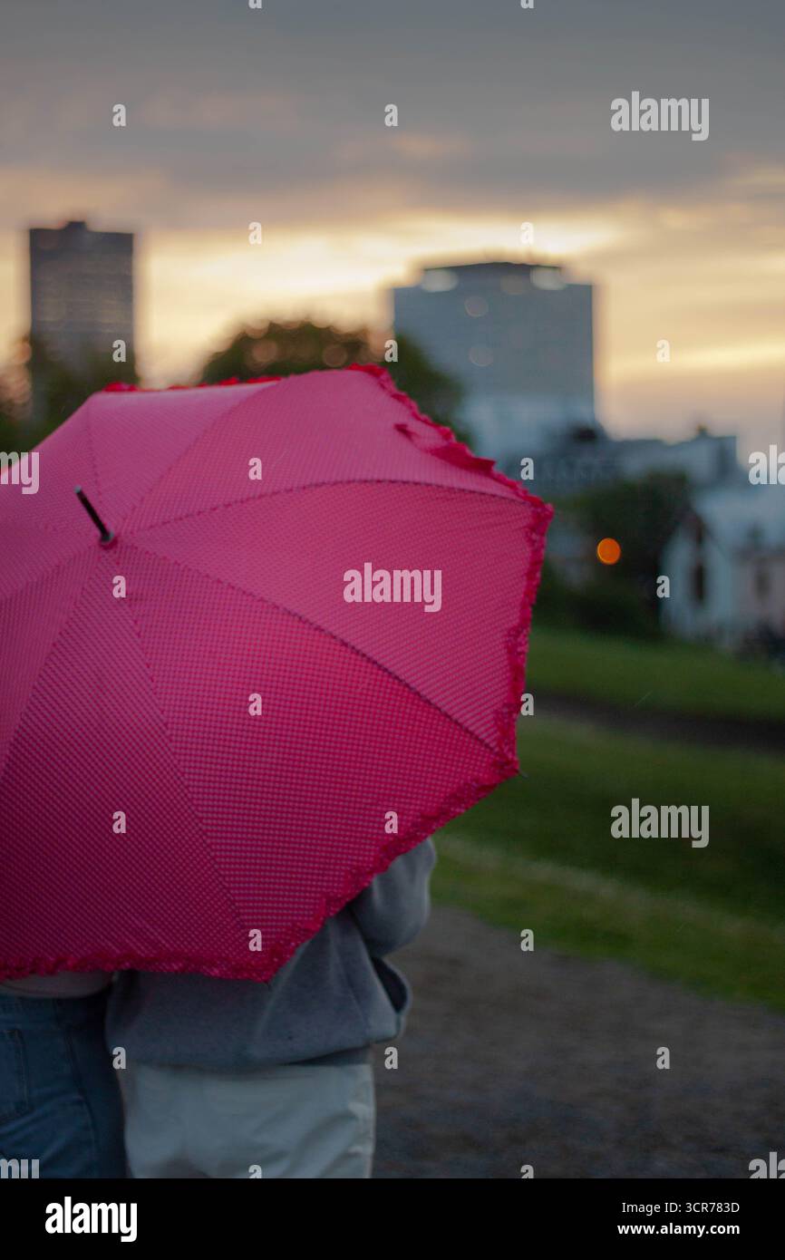 Zwei Frauen unter dem roten Regenschirm beim regnerischen Sonnenuntergang in Quebec City Stockfoto