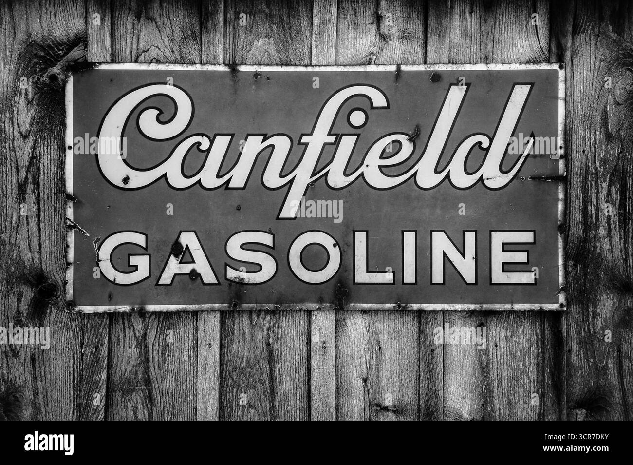 Altes Emaille-Schild von Canfield Benzoline, das an der Seite einer Scheune in Schwarz-weiß hängt Stockfoto
