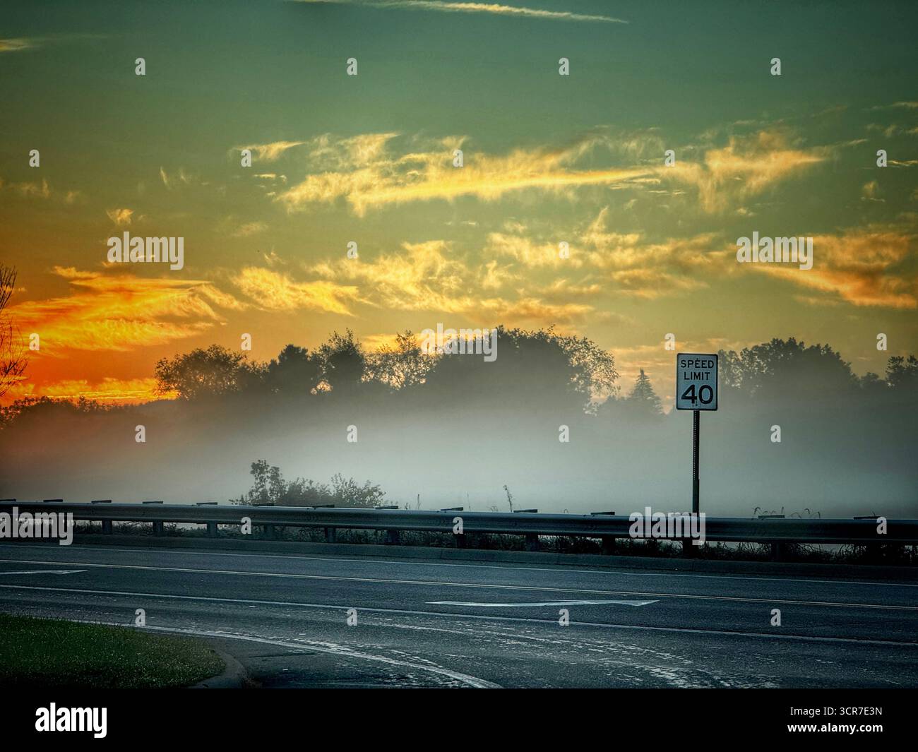Neblige Sonnenaufgangsszene über einer leeren Straße - Smartphone-aufgenommenes Stockfoto