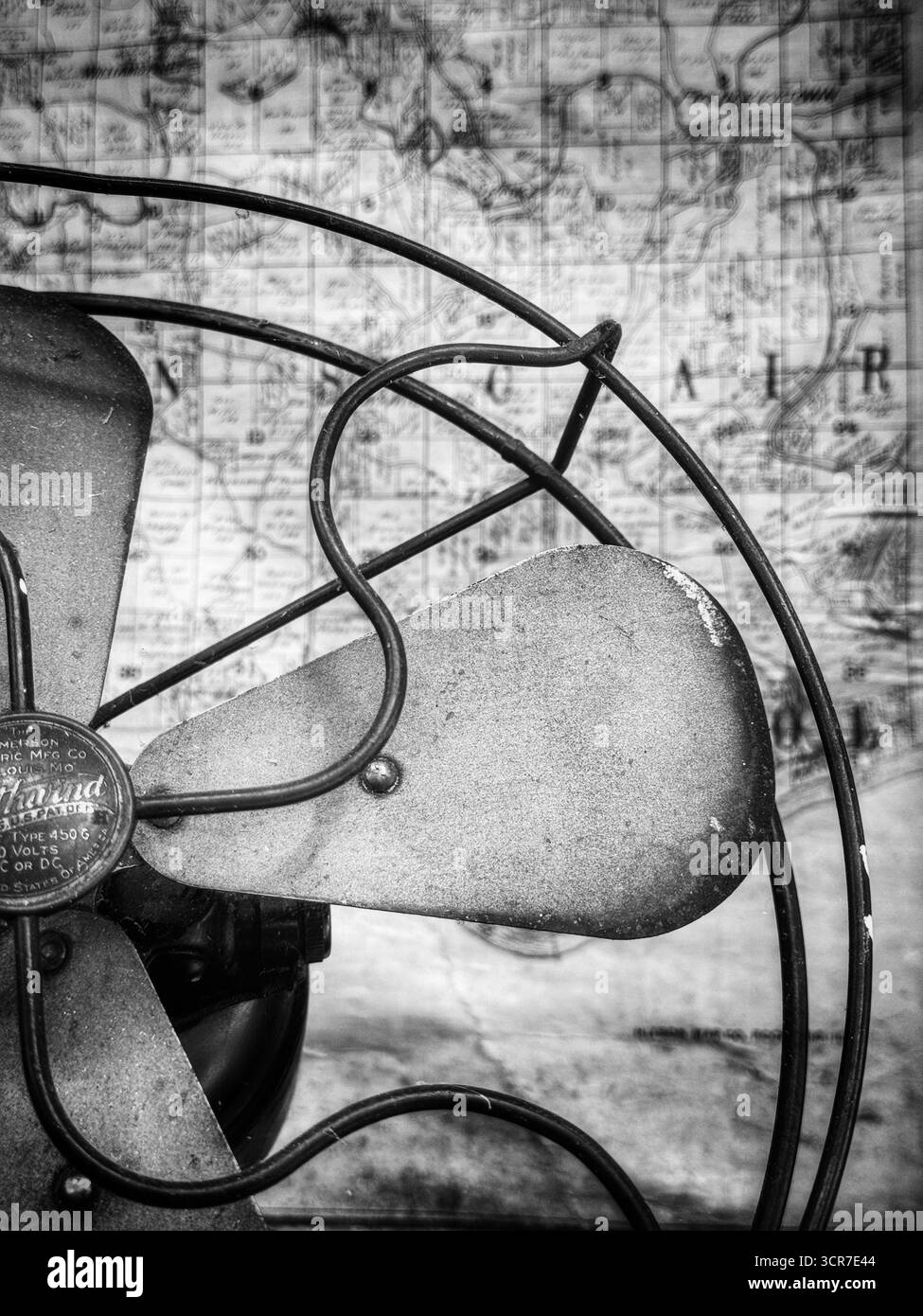 Antiker Metallventilator mit alter Karte im Hintergrund jn schwarz-weiß - Smartphone-aufgenommenes Stockfoto