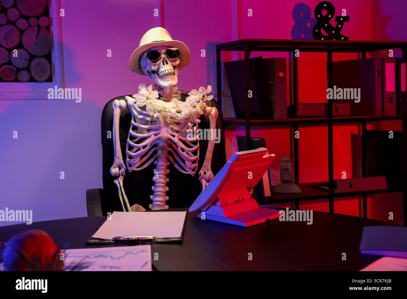 Menschliches Skelettmodell mit Sommerzubehör im Büro bei Nacht Stockfoto