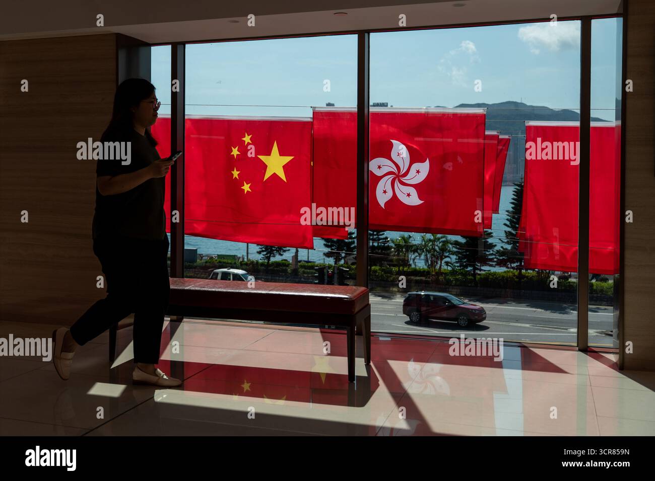 Menschen, die am 30. September 2025 in Hongkong an China National Flags und Hong Kong SAR Flags vorbeilaufen. (Foto von Vernon Yuen/Nexpher Images) Stockfoto