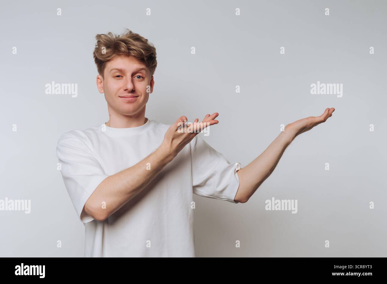 Junger Mann, der in einer zwanglosen Umgebung mit Händen Gesten macht und Enthusiasmus und Engagement auf eine unbeschwerte Weise ausdrückt. Kopierraum Stockfoto