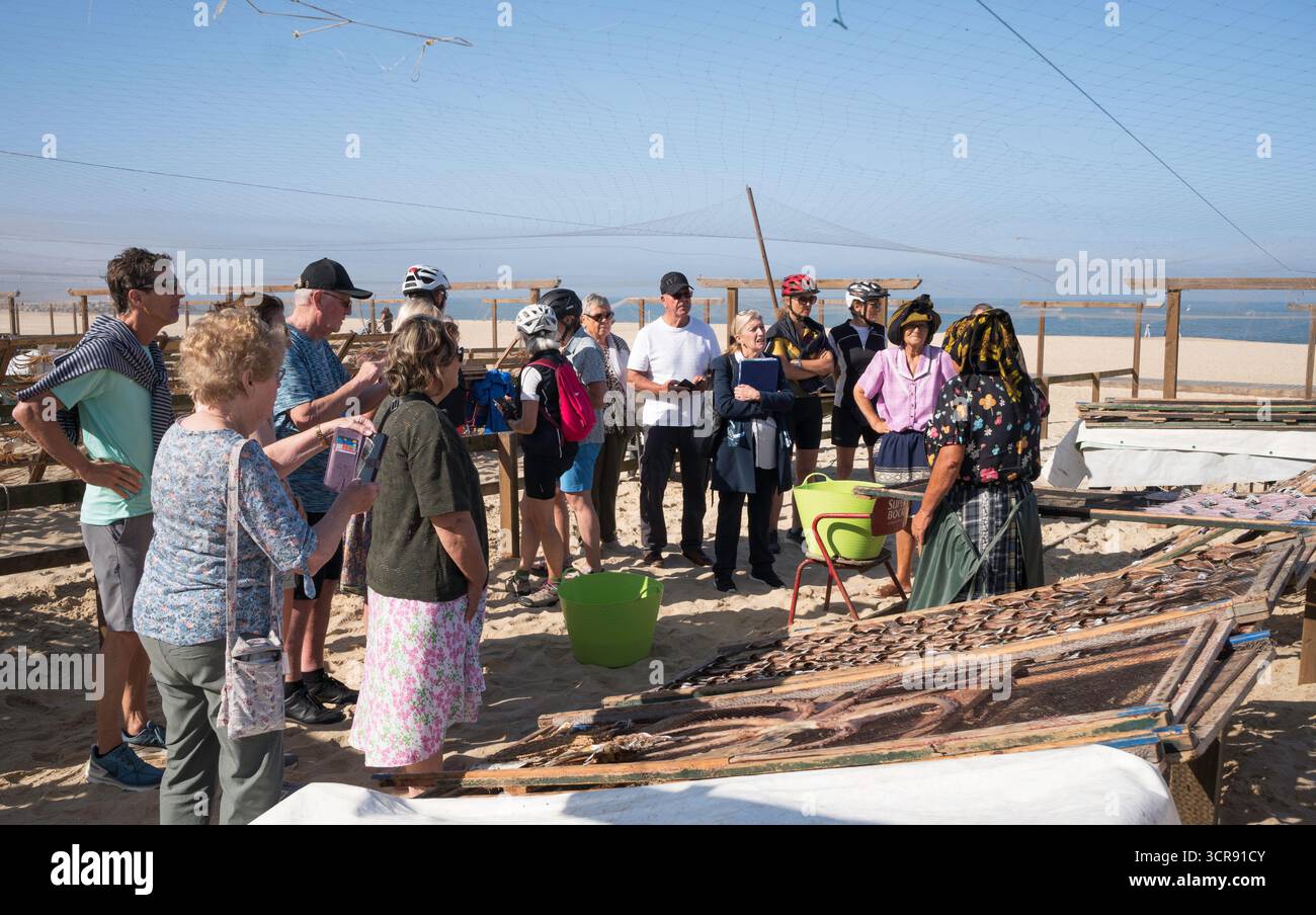 Eine Gruppe von Besuchern beobachtet, wie Fische auf Regalen in Nazaré, Portugal, trocknen Stockfoto