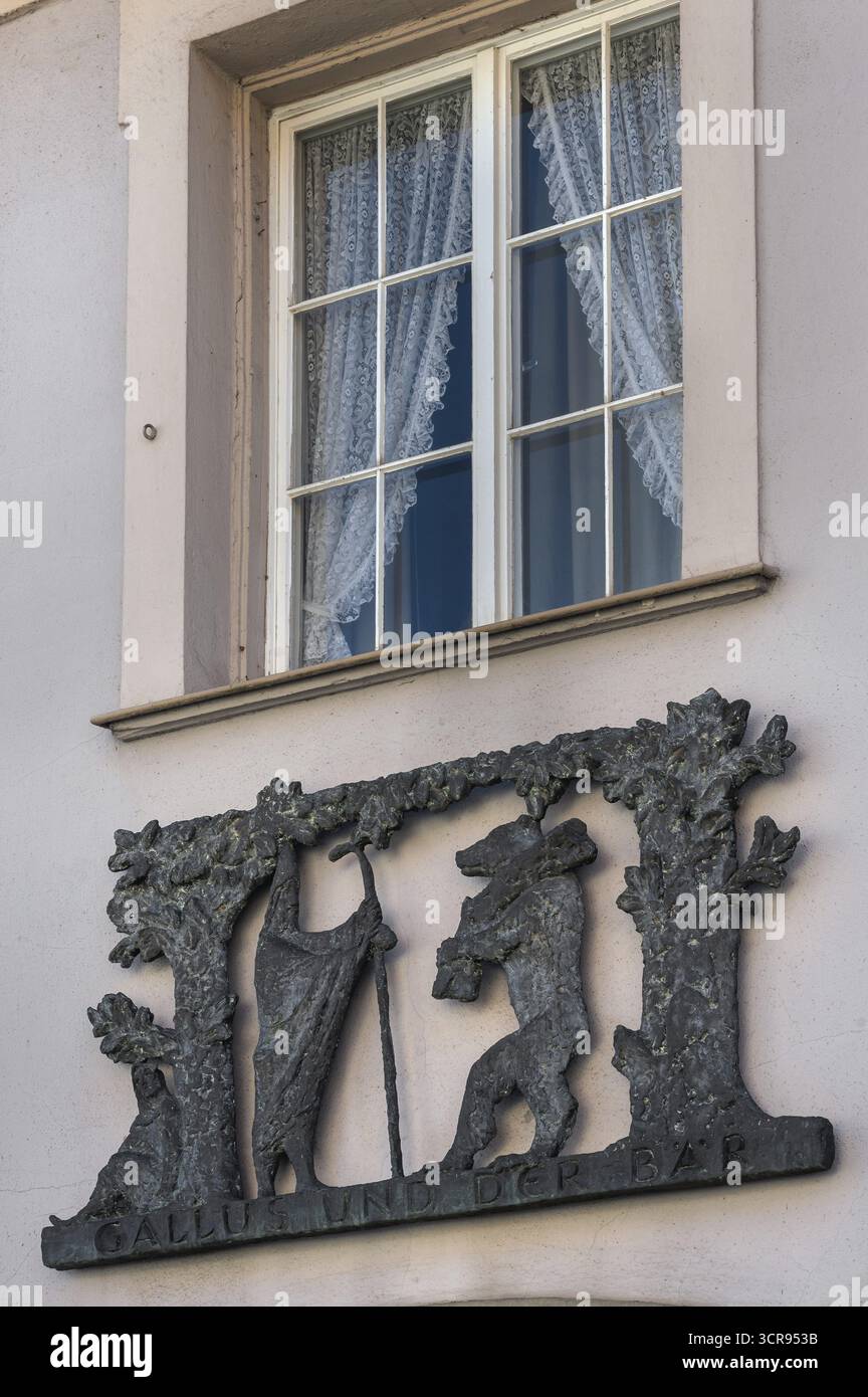 Fenster mit Jalousien und Metallrelief, Gallus und der Bär an der Fassade der Apotheke in Kisslegg, Allgäu, Baden-Württemberg, Deutschland Stockfoto