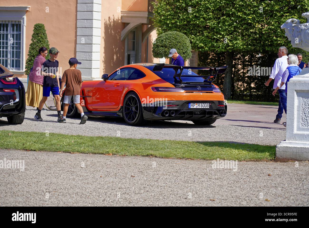 Oldtimer Classic, Gala International Concours d'Elegance Schwetzingen 2025, Deutschland, Europa, ein orangener Sportwagen neben einem Gebäude voller Menschen Stockfoto