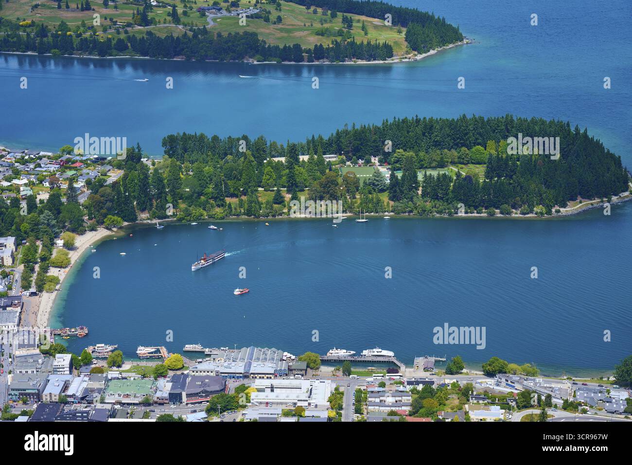 Blick auf eine Bucht mit einer kleinen Insel, umgeben von der Stadt und der natürlichen Umgebung, Queenstown, Queenstown-Lakes District, Otago, Südinsel, Neuer Ze Stockfoto