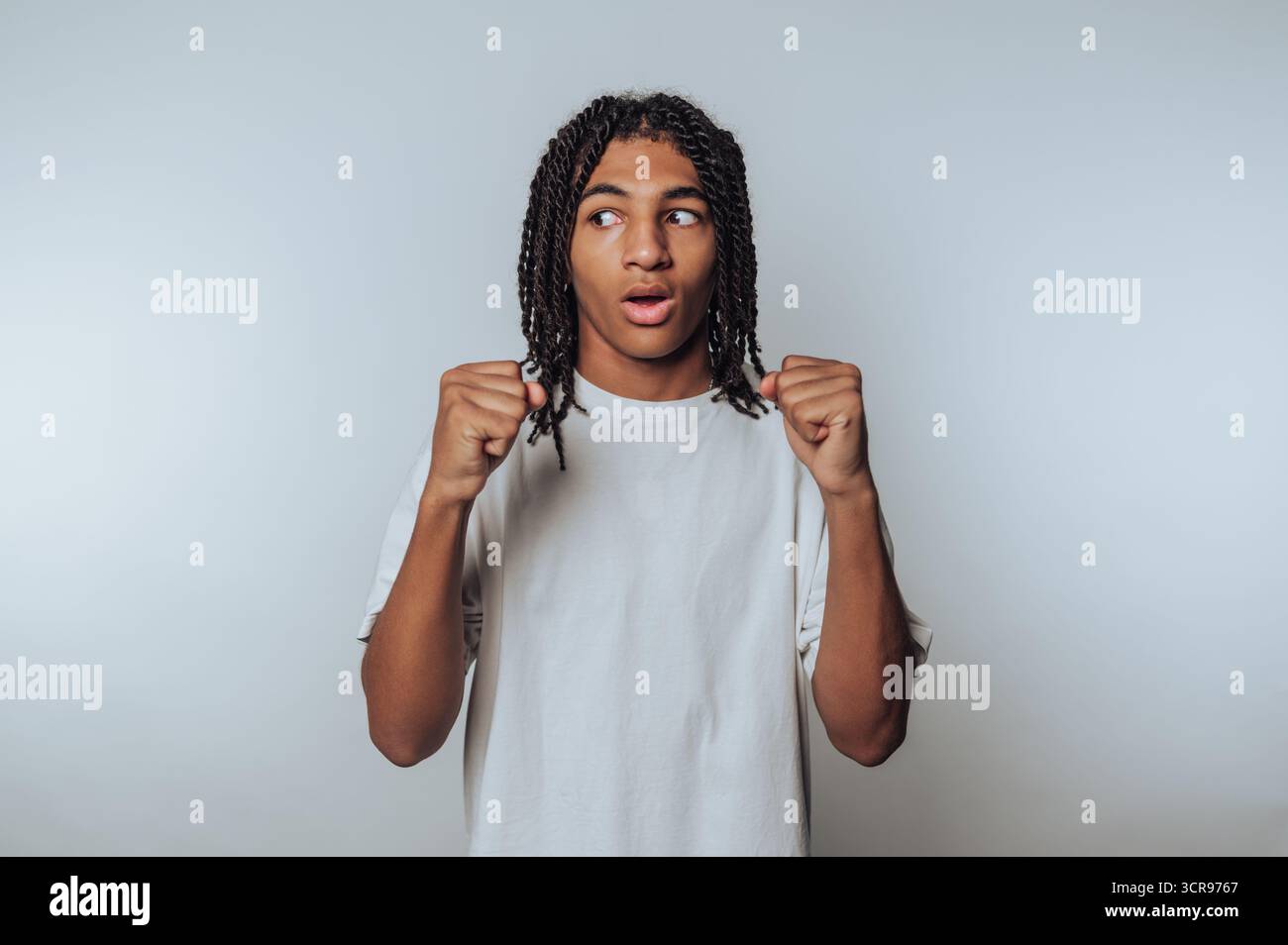 Der junge Mann zeigt eine kämpferische Haltung mit einem überraschenden Blick und hebt Reaktion und Bereitschaft auf weißem Hintergrund hervor Stockfoto