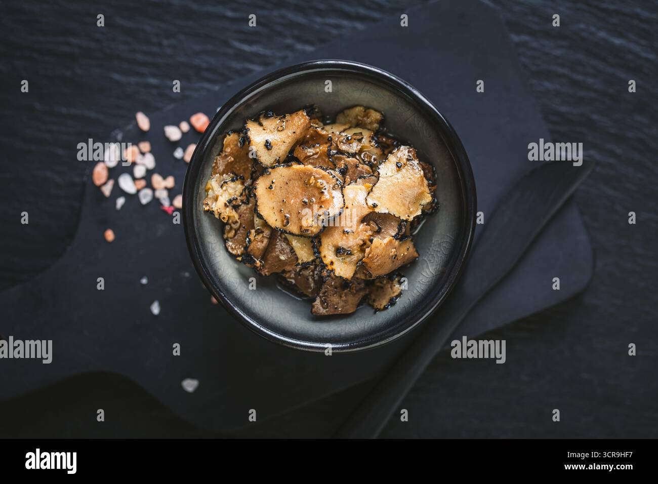 Rustikales Stillleben mit Trüffeln, Trüffelöl und Salz auf einem Holztisch mit Gourmet-Zutaten und kulinarischen Werkzeugen Stockfoto