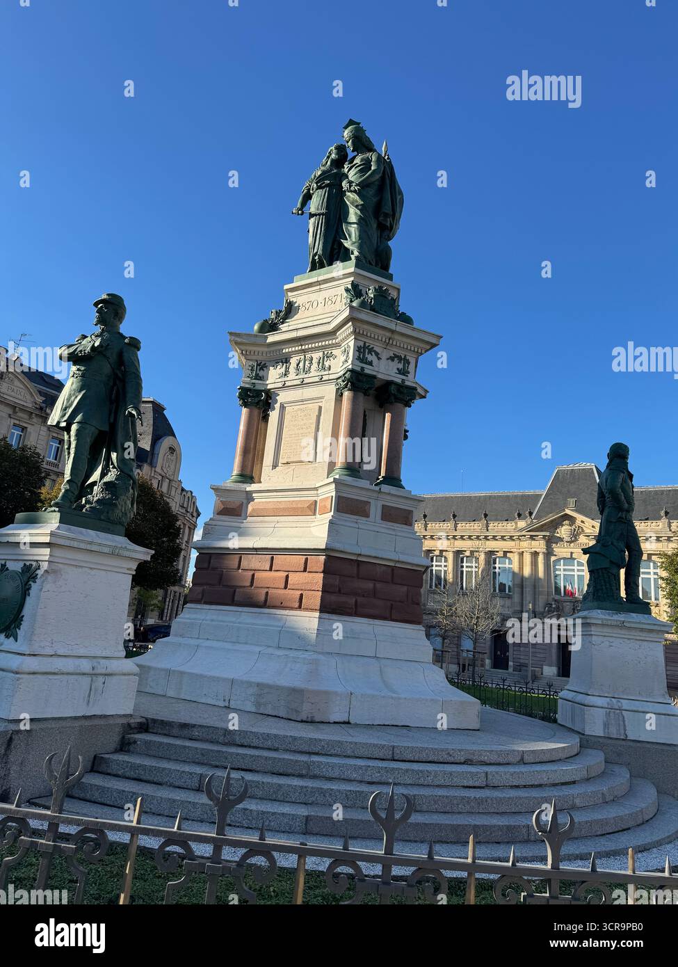Blick auf das Monument des Trois Belages und das Monument lecourbe im Stadtzentrum von Belfort, mit Bronzestatuen vor der historischen französischen Architektur - Smartphone-aufgenommenes Stockfoto