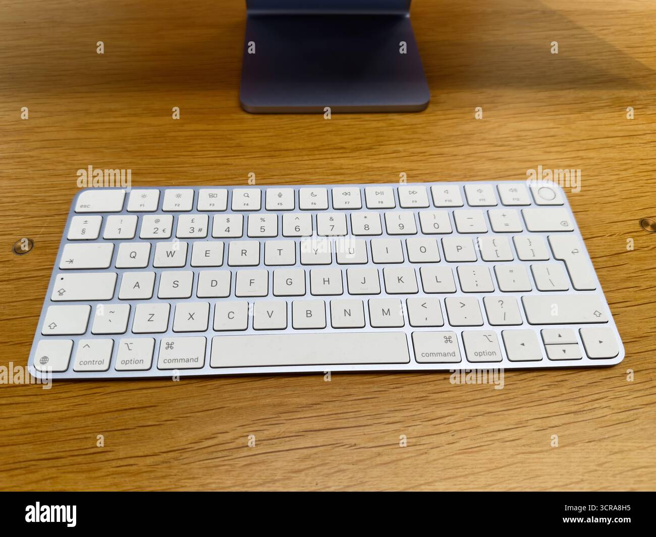 Manchester, Großbritannien – 29. September 2025: Minimalistisches Tischdesign mit weißer Apple Magic Tastatur auf Holz, die für ruhige Produktivität sorgt. Stockfoto