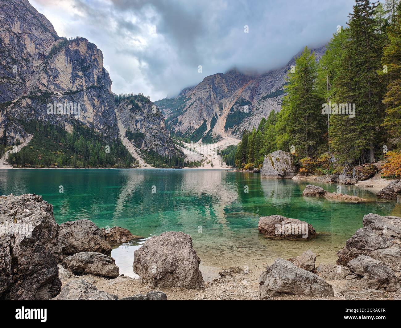 Idyllischer und ruhiger Pragser Wildsee. Malerisches türkisfarbenes Wasser, Felsen, Bäume und bewölkter Himmel. Dolomiten, Italien Stockfoto