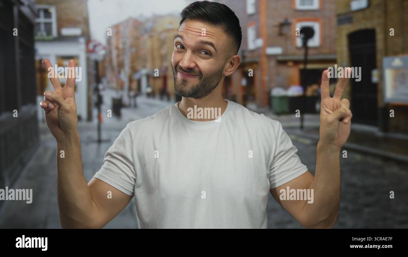 Junger hispanischer Mann, der in einer lebhaften urbanen Straßenszene Luftzitierungen macht und das moderne Stadtleben mit einem verspielten Ausdruck und lässiger Kleidung in einer lebendigen urbanen Straßenszene präsentiert Stockfoto