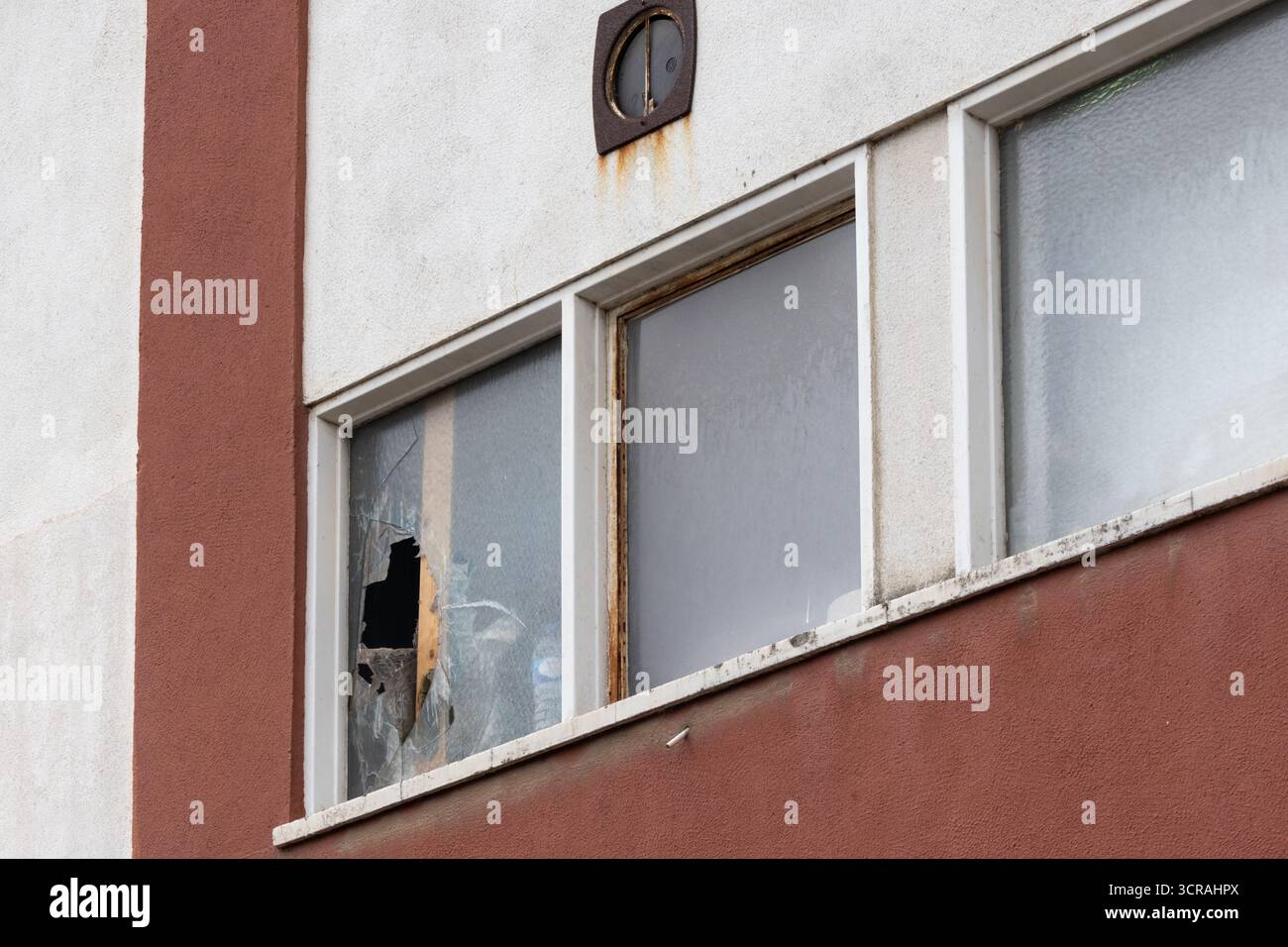 Glasbruch in einem Fenster eines verlassenen Gebäudes offenbart urbanen Verfall und Vandalismus Stockfoto